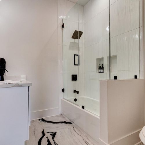 Luxe master bath w/ glass-enclosed shower & rainfall showerhead.