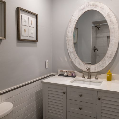 This redesigned bathroom features a new freestanding vanity with reclaimed wood mirror and a walk-in shower.