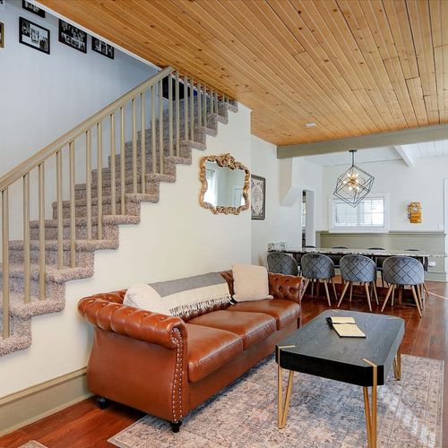 - inviting space with a classic leather sofa, soft carpeting, and decorative wall mirror
- stairway gallery wall adds a personal touch to this charming layout
- seamlessly connects to dining area, making entertaining easy and enjoyable