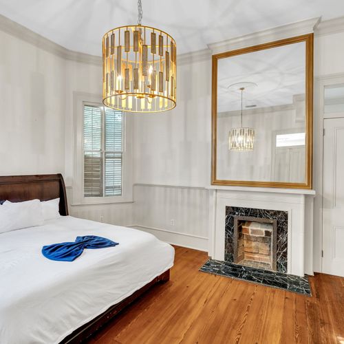 Elegant bedroom with a cozy fireplace and modern chandelier.