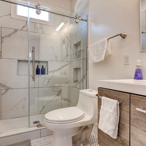 Sleek bathroom w/ marble-look tile, glass shower & modern vanity.