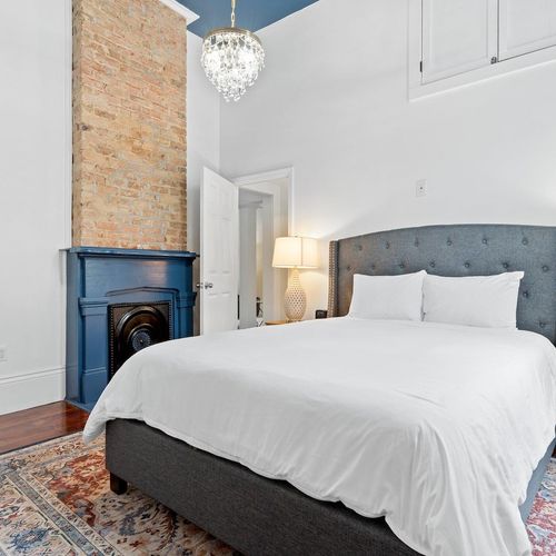 Cozy queen bedroom w/ a tufted headboard, fireplace & crisp white linens for a restful night.