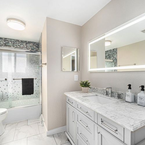 - pamper yourself in this upscale bathroom with a dazzling mosaic tile shower
- marble vanity, glowing backlit mirror, and modern finishes offer a spa like escape
- sleek blend of textures and light makes mornings feel stylish and refreshing
