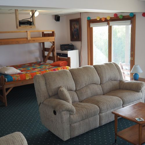 Living room #2 (lower level):  features a sofa and loveseat, bar area, and 3 single beds.