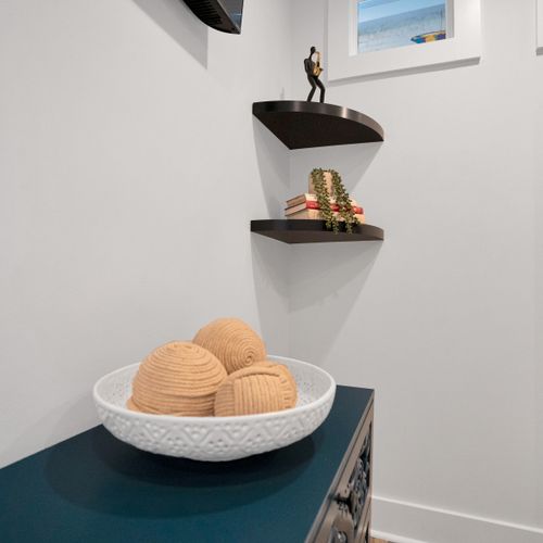 Sculptural woven bowl on a white shelf brings minimalist coastal warmth to the room.