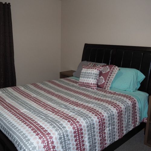 Bedroom #1 (main floor):  features a queen-size bed, nightstands, dresser, mirror, pedestal fan, and closet.