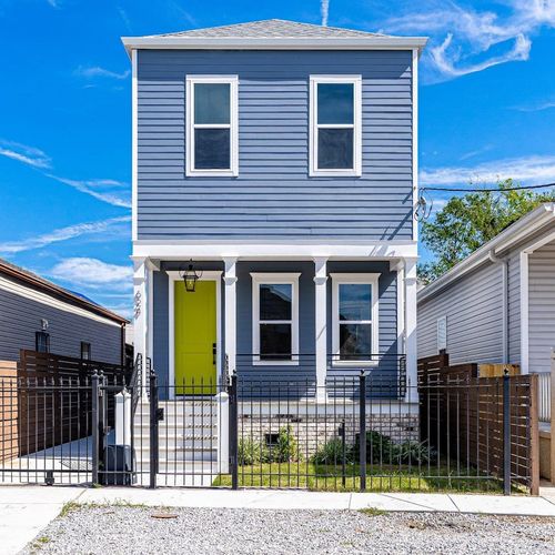 Charming blue home w/ iconic yellow door, inviting curb appeal at its best.