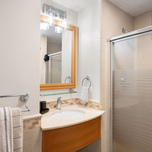 Modern and pristine bathroom featuring a vanity with a stylish mirror and a refreshing shower.