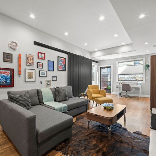 Bright, modern living space with large windows, warm floors, and a comfortable work area.