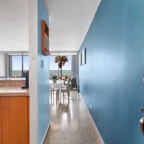 Entryway view of open-concept living space with partial kitchen, leading to dining area, ocean balcony, and natural light.