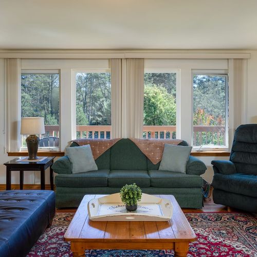 Large windows surround the living room, bringing the flowers and trees indoors.