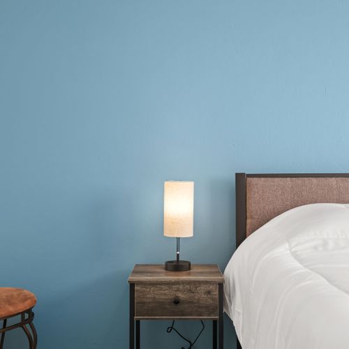 Experimente la tranquilidad en este elegante dormitorio caracterizado por sus elementos de diseño contemporáneo, su acogedora cama y su llamativa pared azul.