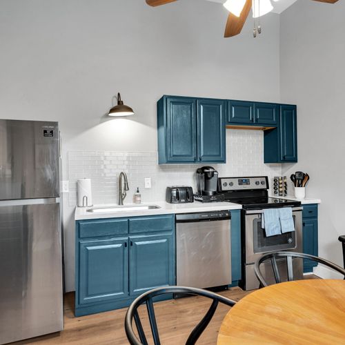 Teal cabinetry & stainless steel appliances in a well-equipped kitchen.