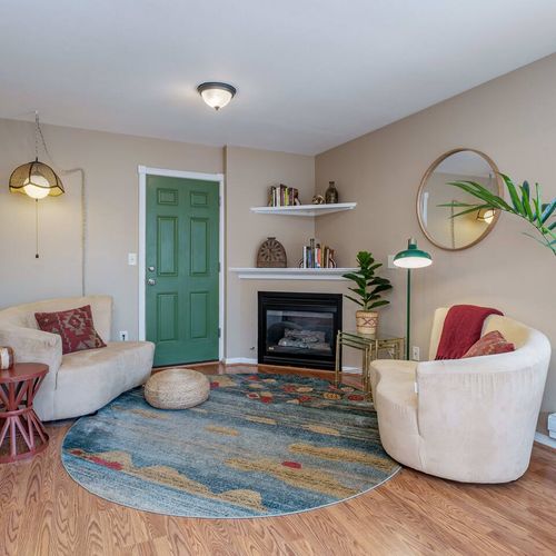 - relax in this charming nook with soft armchairs and a cozy fireplace
- decor includes earthy tones, plants, and stylish shelves for a calming vibe
- unique green door and circular rug add warmth and personality to the space