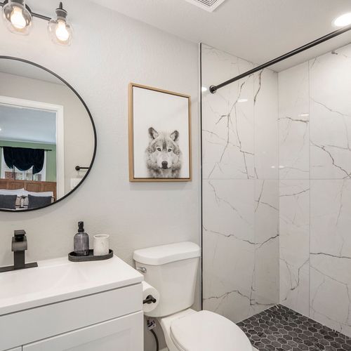 The ensuite bathroom features a spacious walk-in shower and a sleek vanity, creating a luxurious space for relaxation and convenience during your stay.