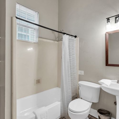 Clean bathroom w/ a tub/shower combo, white tile & plenty of space.