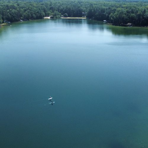 Exterior:  a high-level view of cub lake, with some people paddleboarding across the lake.