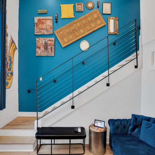 Vibrant teal staircase wall adds a pop of color & artistic energy to the space.