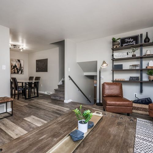 - rustic wood coffee table anchors a living room full of charm and character
- open layout flows to the dining area and stairway creating an airy vibe
- mix of textures from leather wood and steel offers depth and warmth