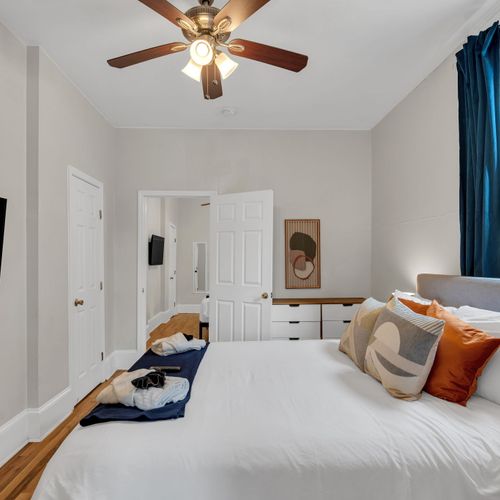 Light-filled bedroom w/ warm tones & a neatly made bed.