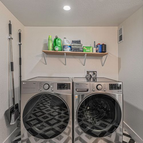 - enjoy the ease of in home laundry with a modern washer and dryer set against eye catching tile
- wall shelf stocked with laundry supplies makes mid stay refreshes effortless
- clean layout blends functionality with a sharp, bold design