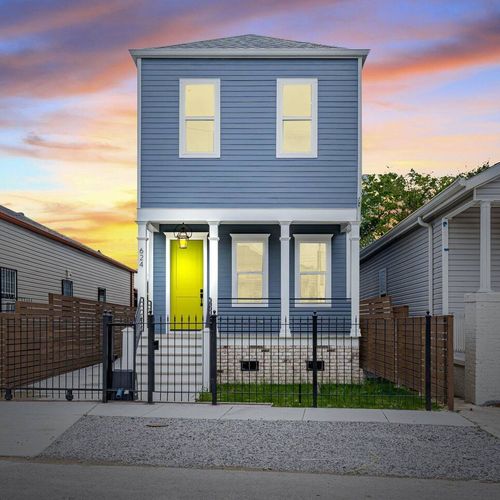Charming blue exterior w/ a bold yellow door glowing at golden hour.