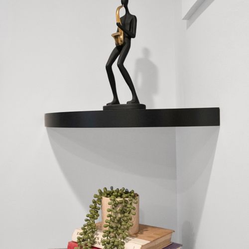 Sleek black shelf w/ a golden sculptural figure adds an artful, modern touch.