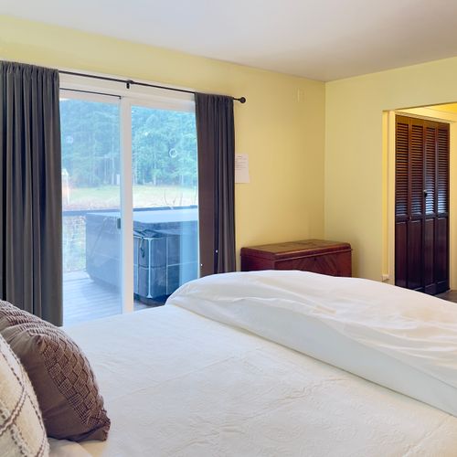 Wake up to forest views and step straight onto the deck for fresh air. This serene bedroom features cozy linens, blackout curtains for restful sleep, and easy access to the outdoor hot tub.