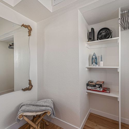 - open closet nook offers handy storage shelves with games, décor, and essentials neatly arranged
- classic mirror adds depth while the bench offers a place to rest or set your bag
- ideal for guests who appreciate thoughtful design and practicality