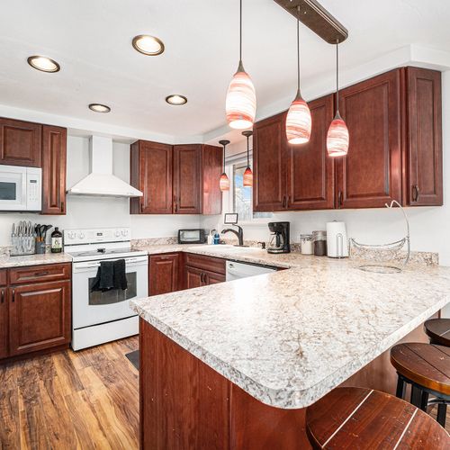 The kitchen complemented by three stools at the counter for a cozy dining experience seamlessly connects to a covered patio through a sliding door.