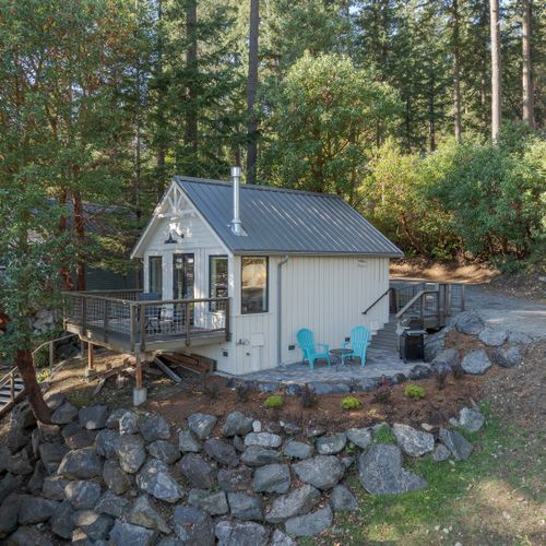 Nestled among towering evergreens, this charming cabin offers a peaceful escape with its wraparound deck, nature views, and quiet outdoor seating, perfect for morning coffee.