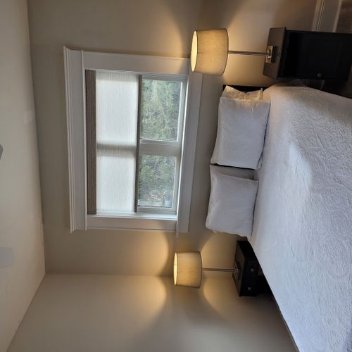 Bedroom #1 (main floor):  features a queen-size bed, ceiling fan, window a/c unit, nightstands, lamps, chair, dresser, mirror, and a closet.