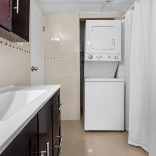 The sink basin is crafted from white ceramic, complemented by a matte black faucet with a waterfall spout.