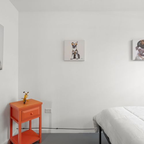 A clean, uncluttered space with a pop of color from an orange nightstand, perfect for a restful stay.