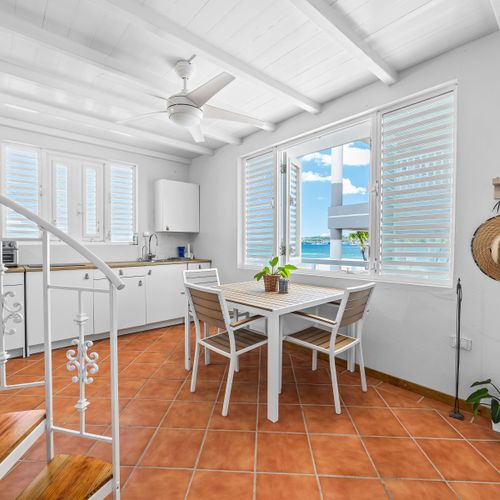 Island-style kitchen with cozy dining space with dining table, ceiling fan