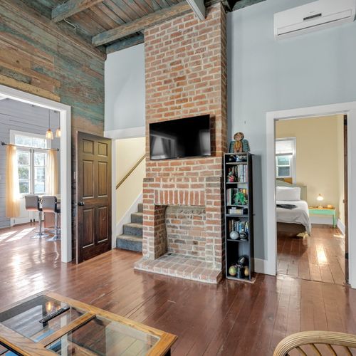 Brick fireplace anchors the living space w/ warmth & classic NOLA character.