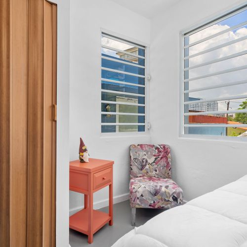 Wake up to the city views in this bright and airy bedroom, featuring a comfortable queen-size bed and modern amenities for a restful stay. The walls are painted white, giving off a bright ambiance.