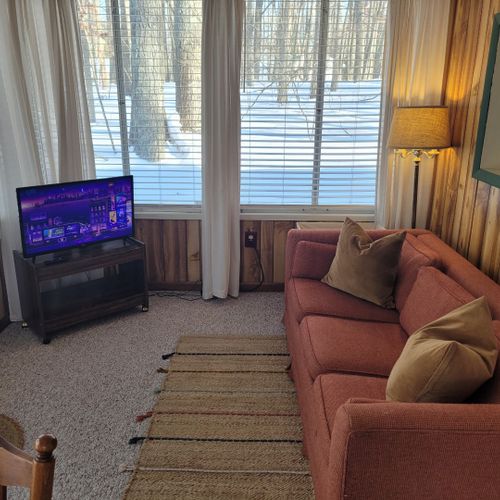 Living room #2:  the cabin has a section that was added on to the original cabin that now includes a sofa, lots of windows, and a smart television with roku.
