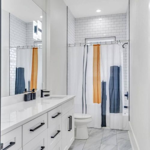 Modern bathroom w/ a sleek wood-paneled accent wall & contemporary fixtures.