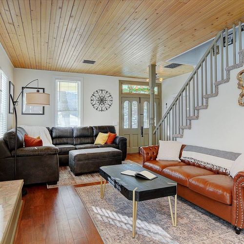 - warm and stylish living room featuring leather and fabric sofas with vibrant accents
- wood paneled ceiling, decorative touches, and stained glass entry add cozy elegance
- fireplace and smart layout create a perfect setting for gathering and unwin