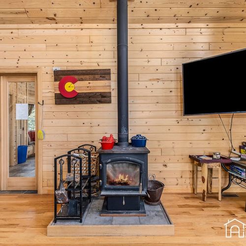 - classic wood burning stove anchors this cozy cabin living area with mountain charm
- mounted flat screen tv and fire tools make this a functional, welcoming space
- ideal for warming up after a snowy hike or a quiet evening in with a movie