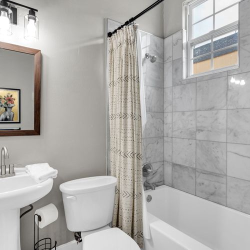 Clean, light-filled bathroom w/ a sink & tub — simple, fresh & functional.