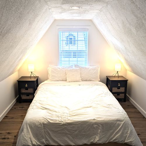 BEDROOM #3 (UPPER LEVEL):  Large and long upper bedroom with a queen-size bed, 2 twin beds, dresser, nightstands, and lamps.