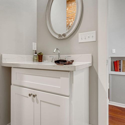 Bright bathroom w/ a round mirror & sink vanity — fresh & functional.