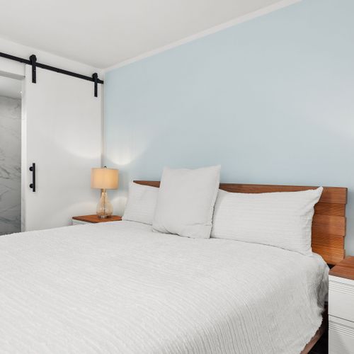 Relaxing bedroom with a modern barn door leading to a luxurious shower