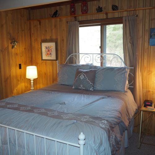 Bedroom #1 (main floor):  features a queen-size bed, chair, dresser, nightstands with lamps, fan, floor lamp, and its own television.