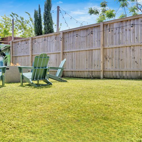 Backyard w/ firepit, green seating, & plenty of room to unwind under the open sky.