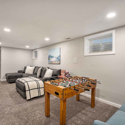 On the lower level, a lounge space awaits, complete with a foosball table and a widescreen tv, perfect for entertainment.