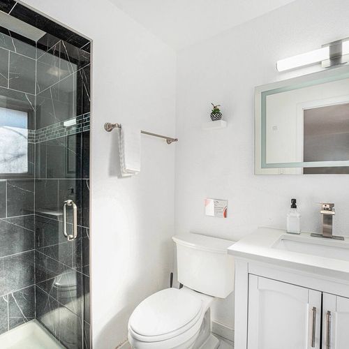 - start your day in this crisp and clean bathroom with spa like black tile finishes
- bright vanity lighting and sleek fixtures elevate your morning routine
- glass door shower and minimalist design make the space feel fresh and inviting
