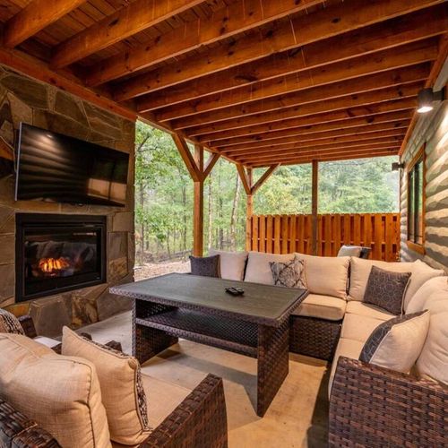 The covered patio hold an oversized outdoor sectional and an outdoor fireplace.